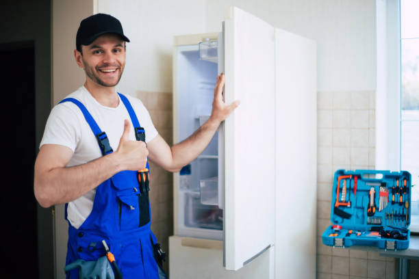 adult repairman holding screwdriver and using digital tablet while repairing washing machine in